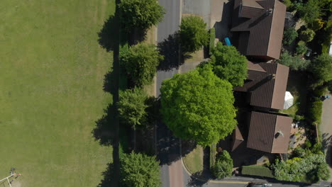 Aerial-shot-looking-down-over-suburban-leafy-neighbourhood-with-cars-and-vans-passing-by