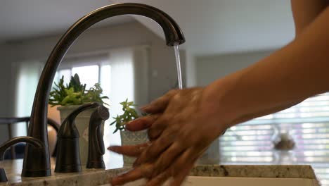 Medium-close-up:-Young-man-washes-dirty-hands-in-modern-kitchen-sink