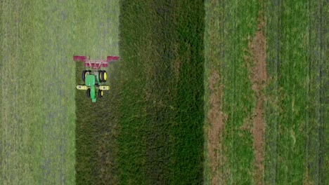 Drone-overhead-shot-of-agriculture-tractor-cutting-field-creating-lines