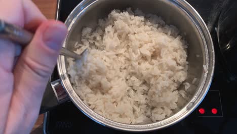 Stir-with-a-fork-in-a-saucepan-with-steaming-rice