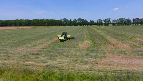 Reversing-drone-shot-of-tractor-harvesting-a-green-field