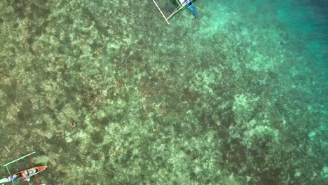 Crystal-clear-shallow-waters-and-boats-in-Philippines,-drone-rising-up-shot-from-a-coral-reef