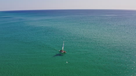 Beautiful-aerial-view-of-a-catamaran-sailing-on-sparkling-blue-tropical-water