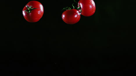 Zeitlupe---Aufnahme-Von-Drei-Leckeren-Tomaten,-Die-Vor-Schwarzem-Hintergrund-Durch-Die-Luft-Fliegen
