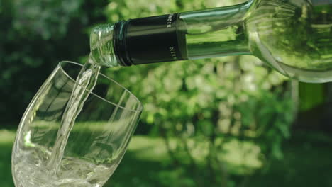 Slow-Motion---Close-shot-of-delicious-white-wine-poured-into-a-glass-in-the-garden-on-a-sunny-day