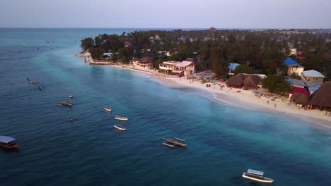 Drone-Aerial-Pullback-of-a-Popular-Tourist-Hotspot-During-Sunset,-Nungwi-Beach,-Zanzibar,-Island-in-Tanzania