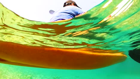 Man-paddling-canoe-during-summer-vacation-on-beautiful-shot-under-the-clean-sea-water-in-slow-motion