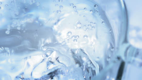 Zeitlupe---Nahaufnahme-Eines-Eiswürfels,-Der-In-Ein-Kaltes-Und-Erfrischendes-Glas-Mineralwasser-Fällt