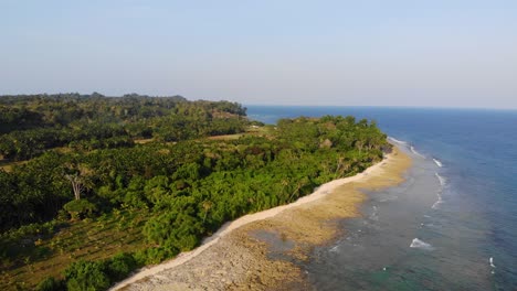 Forward-drone-motion-view-of-ancient-volcanic-andaman-island-in-late-afternoon-light-with-the-andaman-sea-in-the-background-and-farmland-in-the-foreground-with-small-homesteads-,-forest-and-fields
