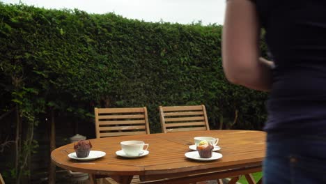 Tea-and-muffins-in-the-garden-white-china-tea-cups-and-saucers-on-wooden-table-buns