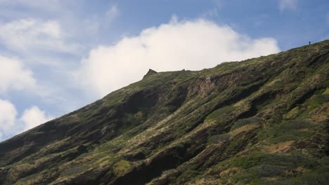 Un-Excursionista-Solitario-Se-Para-Y-Examina-La-Vista-Desde-Lo-Alto-De-Un-Afloramiento-De-Oahu-Con-Cielos-Azules-Y-Nubes-Detrás