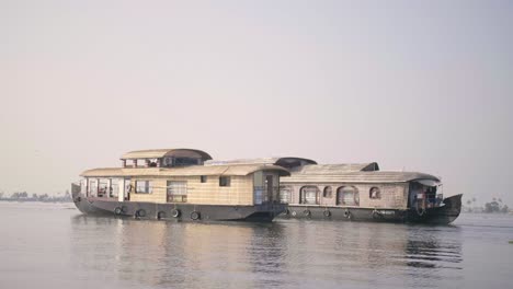 Die-Kamera-Segelt-Mit-Einer-ähnlichen-Geschwindigkeit-Wie-Zwei-Hausboote,-Die-In-Der-Späteren-Nachmittagssonne-über-Das-Glas-Gleiten-Wie-Die-Backwaters-Von-Kerala