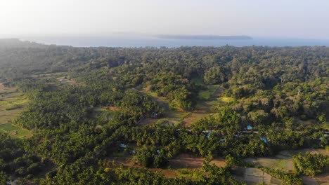 Panoramic-drone-view-of-andaman-island-with-remote-island-in-the-background-and-farmland-in-the-foreground-with-small-homesteads-,-forest-and-fields