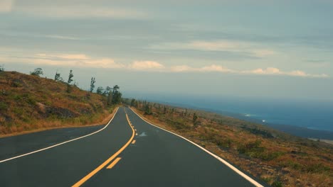 Conduciendo-Hacia-El-Océano-Pacífico-Desde-El-Volcán-Mauna-Kea-A-La-Luz-De-La-Tarde-Con-Flujos-De-Lava-Visibles-En-El-Fondo