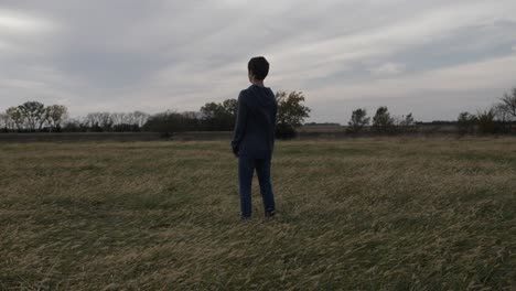A-teen-boy-stands-in-a-Kansas-field-by-himself-watching-the-sun-setting