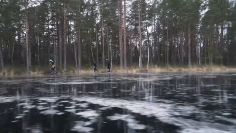 Vista-Lateral-Dinámica-De-Tres-Amigos-Patinando-Sobre-Hielo-En-Un-Lago-Salvaje-En-Letonia