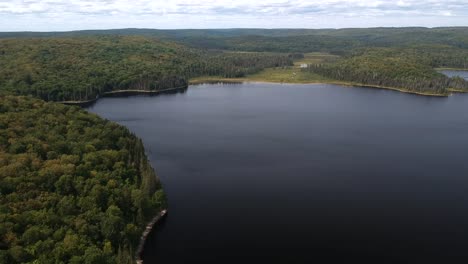 Downward-panning-drone-shot-of-otter-lake-with-beautiful-green-trees-in-the-distance-in-the-rural-countryside-of-North-bay,-Northern-ontario,-Canada