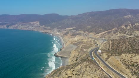 Trucks-and-cars-traveling-a-beautiful-seaside-highway-in-Valle-of-Guadalupe,-Baja-California,-Mexico