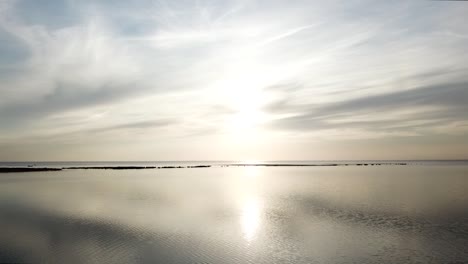 Sun-shining-over-a-flat-Baltic-sea-on-a-windless-day-in-Estonia-creating-mirror-like-effect