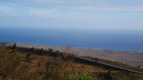 Conduciendo-Por-El-Lado-Del-Volcán-Mauna-Kea-En-Hawaii-Mirando-Hacia-El-Vasto-Océano-Pacífico-Con-El-Sinuoso-Camino-Y-Los-Flujos-De-Lava-Debajo