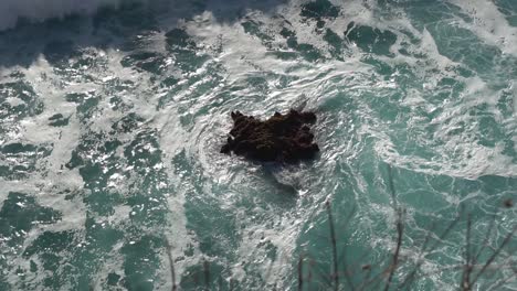 Weißware-Welle,-Die-über-Einen-Unbedeckten-Teil-Eines-Dunklen-Riffs-In-Bali,-Indonesien,-Rollt