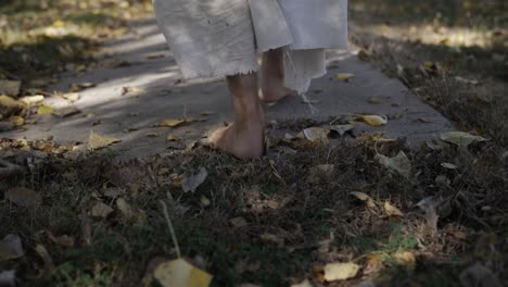 A-dramatic-slow-motion-closeup-of-the-feet-of-a-middle-eastern-man-dressed-as-Jesus-Christ-walking-down-a-sidewalk-while-he-wears-a-white,-tattered-robe