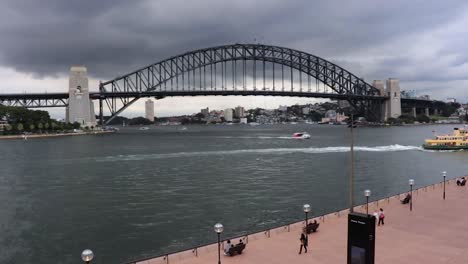 Zeitraffer-Der-Sydney-Harbour-Bridge-In-Australien-An-Einem-Bewölkten-Tag-Mit-Vorbeifahrenden-Booten-Und-Passanten