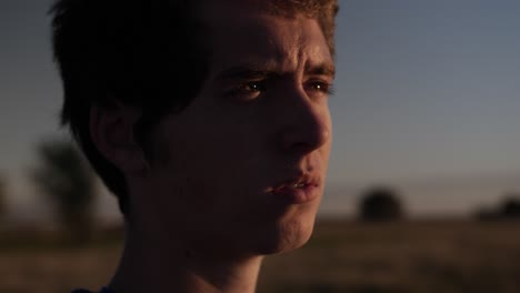 Closeup-of-a-young-teen-boy-standing-in-a-field-watching-the-sun-setting