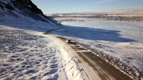 Drone-Sigue-Coche-En-Camino-De-Ripio-Helado-En-Desierto-Islandés