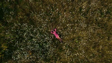 Drohnenaufnahme-Aus-Der-Vogelperspektive-Einer-Schönen-Jungen-Frau,-Die-Auf-Einem-Blumenfeld-In-Der-Landschaft-Kanadas-Liegt-Und-Sich-Entspannt