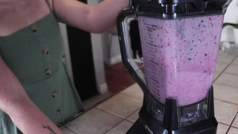 Slow-motion-tight-show-of-girl-blending-a-blueberry-smoothie-in-her-kitchen-with-only-her-hands-showing-in-the-shot