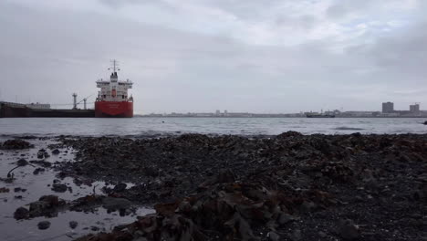Timelapse-of-Reykjavik-old-harbour-area,-docked-ship,-sea-tide-coming-in-on-black-beach-shoreline