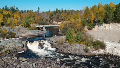 Downwards-panning-drone-shot-of-a-beautiful-waterfall-and-a-flowing-river-during-the-fall-season-in-Canada