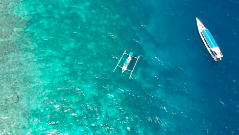 Aerial-drone-shot-of-a-traditional-Indonesian-canoe-for-jukung-diving-that-is-located-just-off-the-tropical-coast-of-the-Gili-Islands-and-is-surrounded-by-crystal-clear-water-and-coral-in-Indonesia