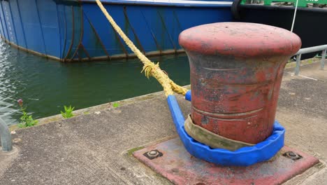 Mooring-post-for-boat-in-harbour-seafront-yellow-rope-blue-boat