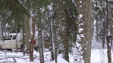 Weißer-Suv-Zieht-Einen-Kleinen-Anhänger-Durch-Einen-Verschneiten-Immergrünen-Wald-In-Lettland,-Nordeuropa