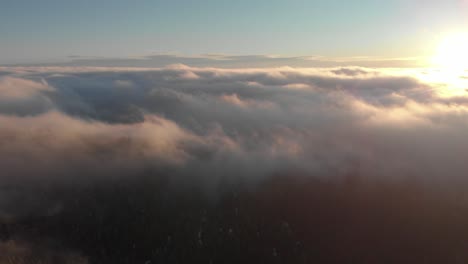 Aerial-pan-over-foggy-mountainside-sunrise-to-sun-over-sea-of-cloud