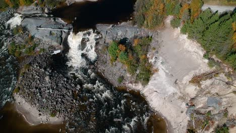 Top-down-drone-shot-of-a-beautiful-waterfall-during-the-peak-fall-season-in-the-secluded-forest,-Ontario,-Canada