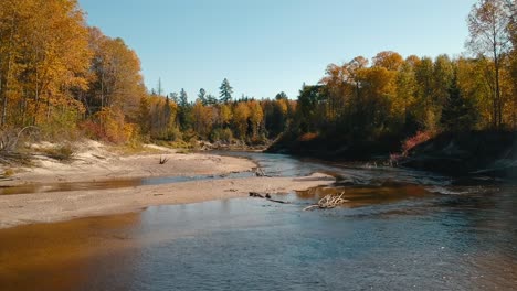 Drohnenaufnahme-Einer-Wunderschönen-Herbstszene-Mit-Einem-Fluss,-Der-In-Der-Ländlichen-Landschaft-Kanadas-Fließt