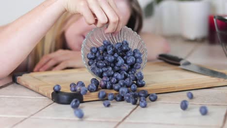 Slow-motion-shot-of-beautiful-blonde-women-dumping-a-bowl-of-blueberries-all-over-her-kitchen-counter