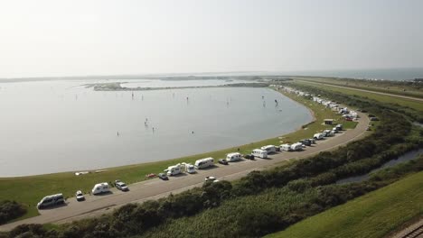 Line-of-campers-parked-and-people-windsurfing-on-Brouwersdam-in-The-Netherlands-during-a-summer-day