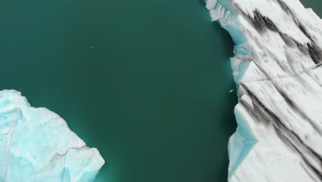 Top-down-areal-drone-shot-of-Jokulsarlon,-the-biggest-and-most-famous-glacier-lake-of-Iceland