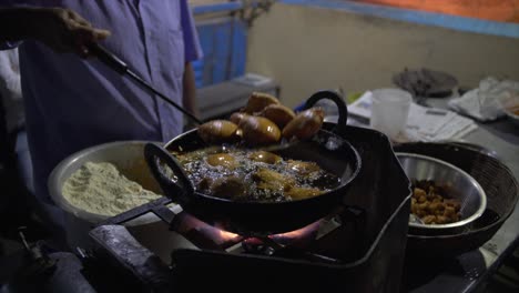 The-fried-street-food-is-lifted-out-of-the-cast-iron-pot-of-oil-for-draining-and-drying