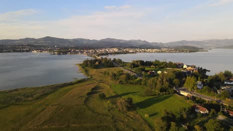 Aerial-drone-shot-flying-backwards-revealing-Rapperswil-and-Hurden-during-a-summer-sunset