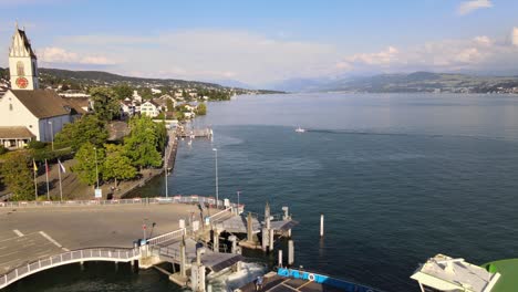 Aerial-drone-shot-flying-backwards-revealing-car-ferry-leaving-Meilen,-Switzerland