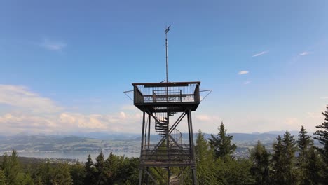 Aerial-close-drone-shot-flying-up-and-tilting-down-showing-the-Pfannenstiel-observation-tower-in-the-canton-of-Zürich,-Switzerland-revealing-the-lake-in-the-background