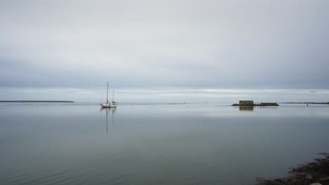 Lonely-boat-on-water-beside-small-island-grey-day-horizon