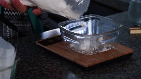 Weighing-flour-for-brownies-in-a-glass-bowl-and-bamboo-scale