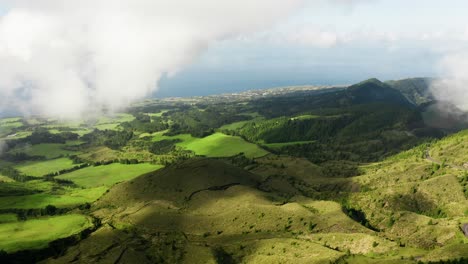 Aerial-push-out-of-shoreline-and-lush-landscape-with-clouds-shadows---São-Miguel,-Azores