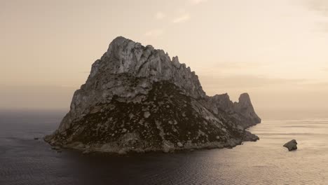 Luftaufnahme-Bei-Dunstigem-Sonnenuntergang-Mit-Blick-Auf-Die-Insel-Der-Felsformation-In-Es-Vedra,-Ibiza,-Spanien